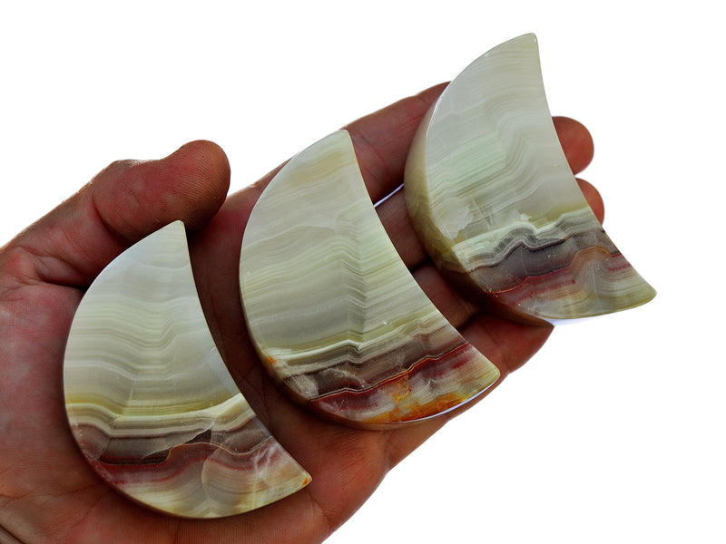 Three pink banded onyx moon minerals 60mm on hand with white background