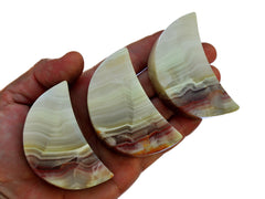 Three pink banded onyx moon minerals 60mm on hand with white background