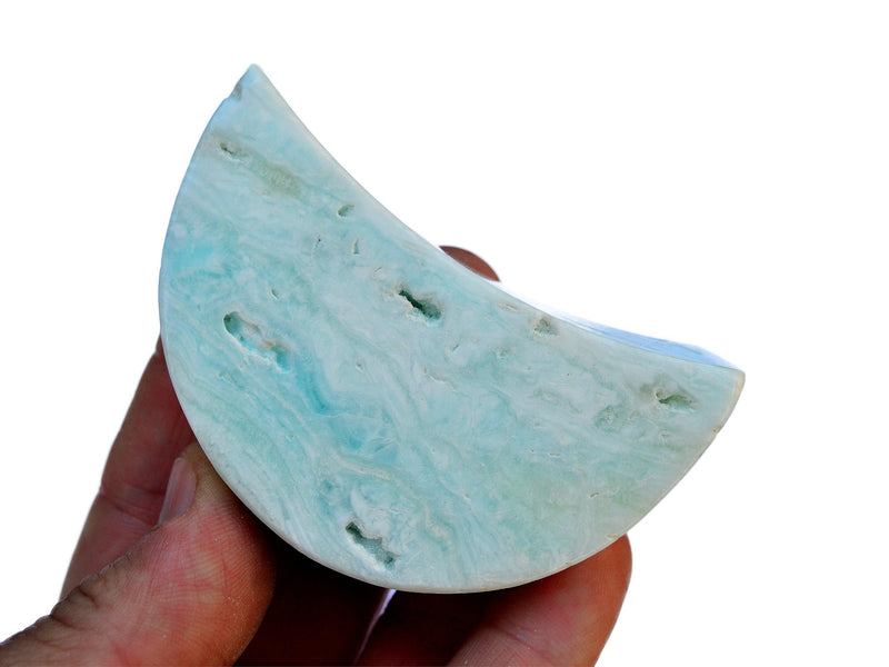 One blue caribbean calcite moon shapped crystal 65mm on hand with white background 