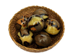 Some yellow septarian crystal balls 50mm inside a straw basket on white background