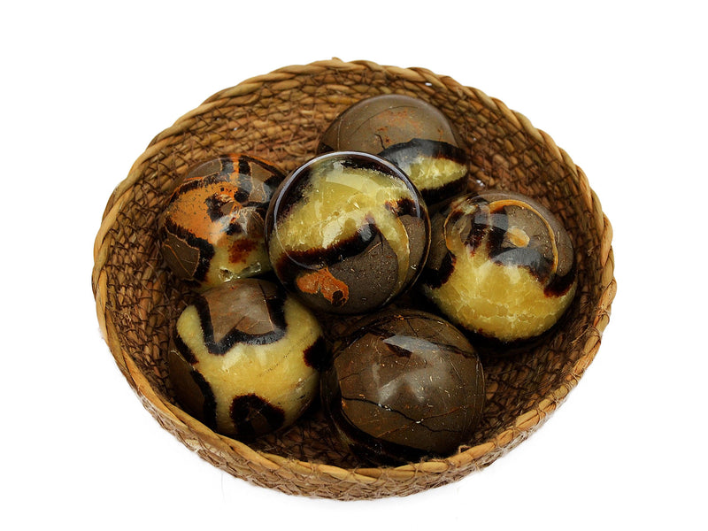 Some yellow septarian crystal balls 50mm  inside a straw basket on white background
