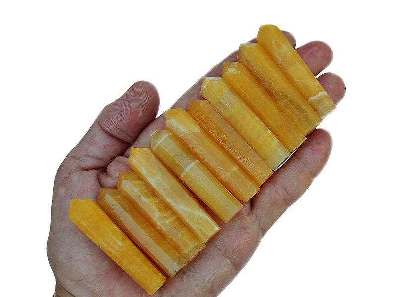 Ten smmal orange calcite faceted crystal points on hand with white background