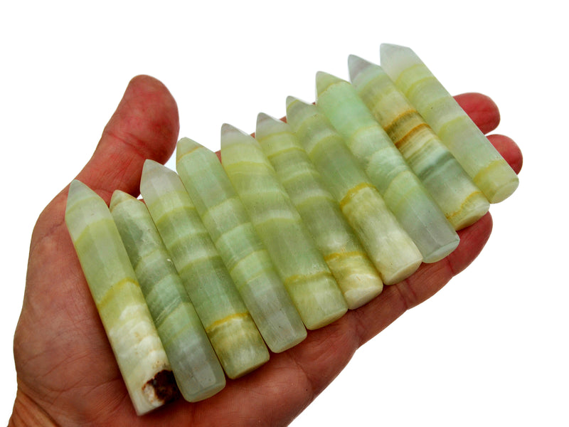 Ten green pistachio calcite crystal points 65mm-70mm on hand with white background