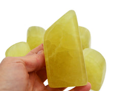 One large lemon calcite free form crystal 100mm on hand with background with some stones