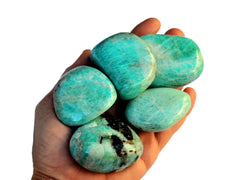 Four large green amazonite tumbled crystals on hand with white hackground