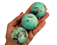 Three amazonite sphere crystals 45mm-55mm on hand with white background