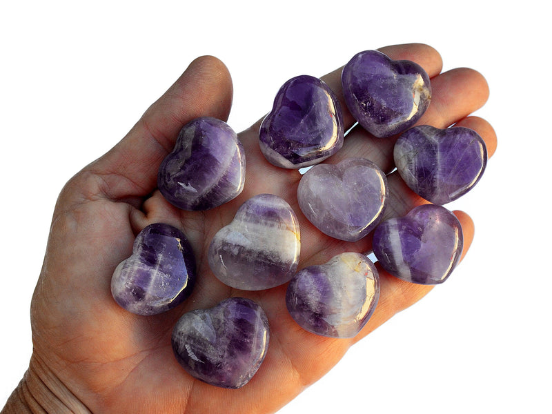 Ten small amethyst crystal hearts 30mm on hand with white background