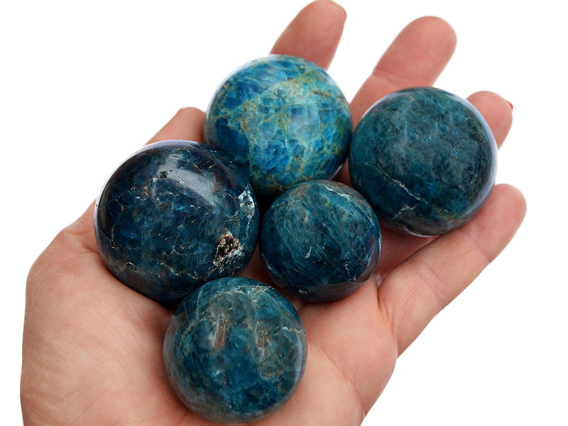 Some blue apatite crystal spheres 25mm-40mm on hand with white background