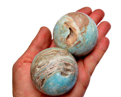 Two blue aragonite spheres 55mm on hand with white background