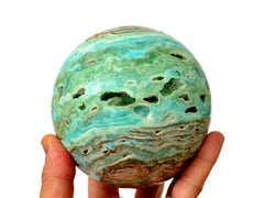 Large blue aragonite sphere 90mm on hand with white background