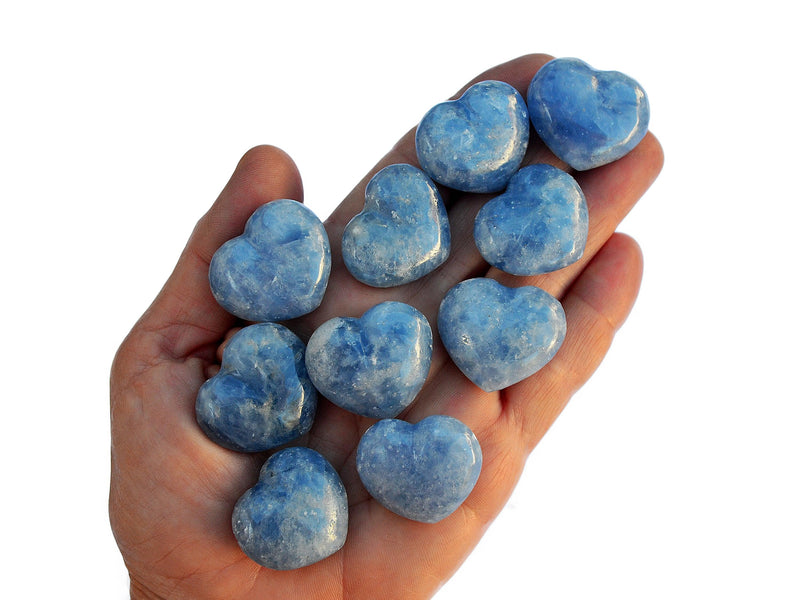 Ten small blue calcite hearts 30mm on hand with white background