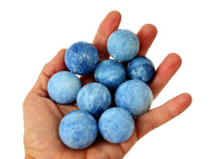 Some small blue calcite spheres 25mm-45mm on hand with white background