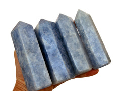 Four blue calcite crystal towers 110mm-125mm on hand with white background