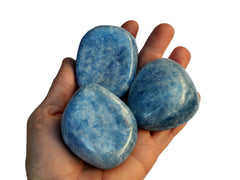 Three large blue calcite tumbled stones on hand with white background