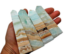 Four large caribbean calcite shaped points on hand with white background