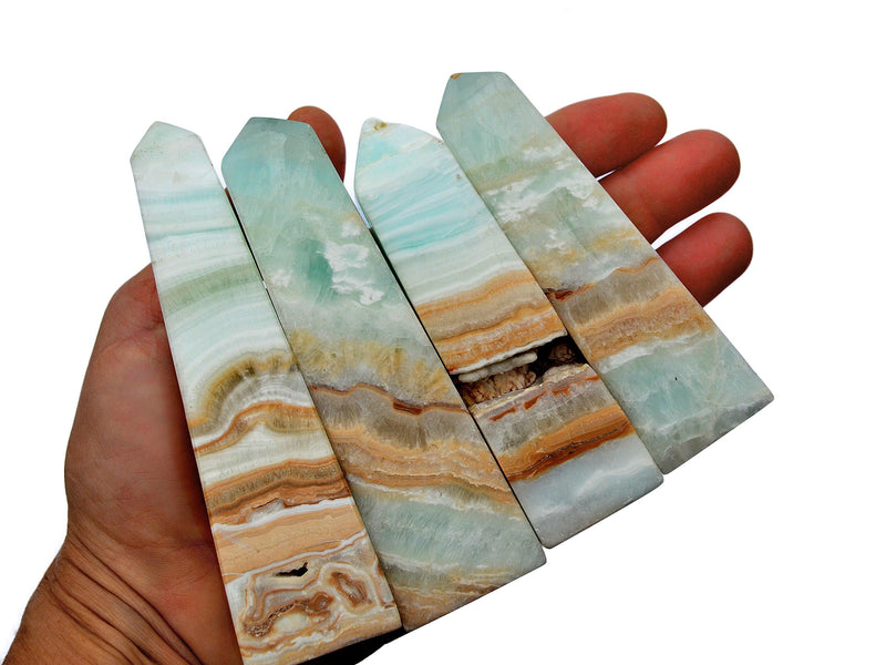 Four caribbean calcite crystal obelisks 65mm-110mm on hand with white background