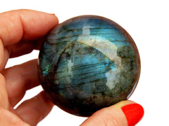 One large blue labradorite sphere 60mm on hand with white background
