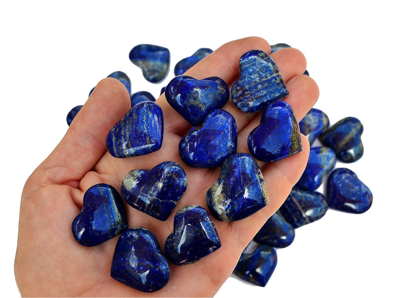 Ten lapis lazuli crystal hearts 30mm-35mm on hand with some stones on white