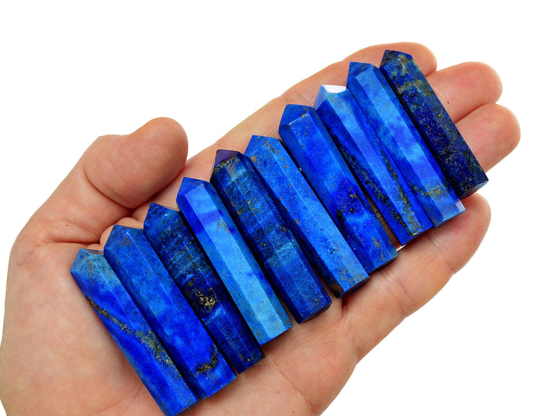 Ten lapis lazuli faceted crystals points 50mm on hand with white background