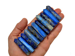 Eleven lapis lazuli faceted crystals points 40mm-50mm on hand with white background