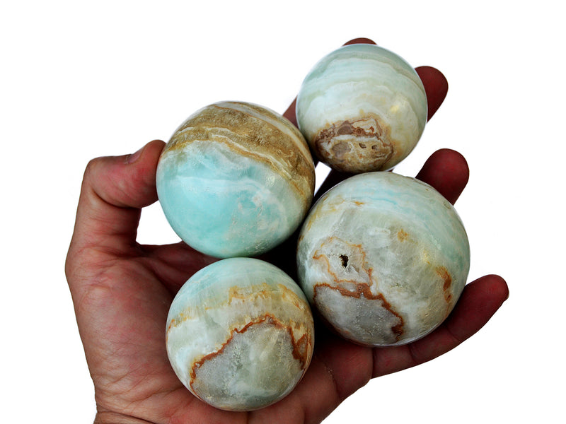 Four caribbean calcite spheres 40mm-60mm on hand with white background