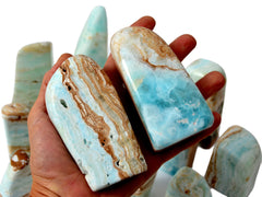 Two caribbean calcite free forms on hand with background with some crystals on white.