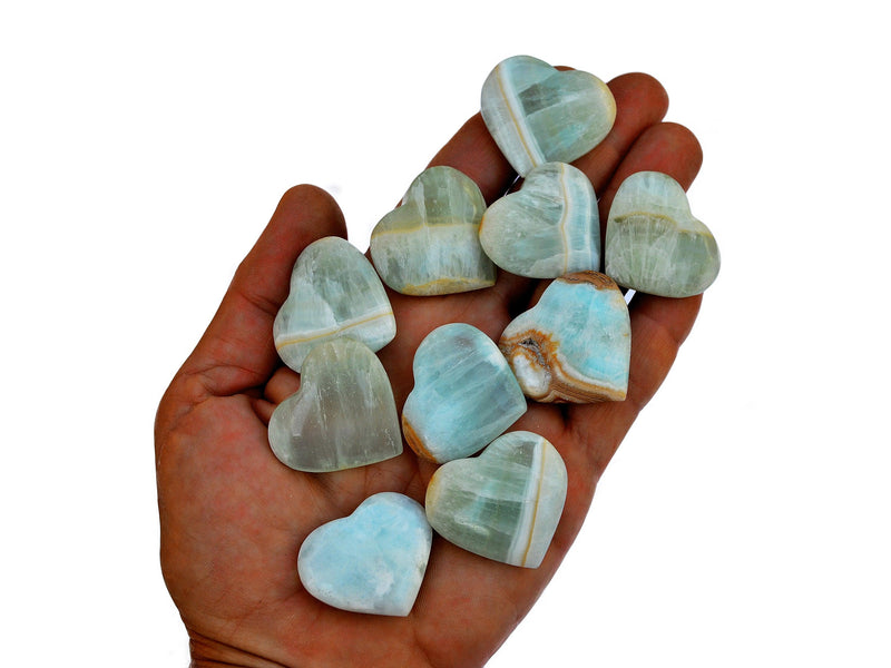 Ten blue green caribbean calcite crystal hearts 25mm-30mm on hand with white background