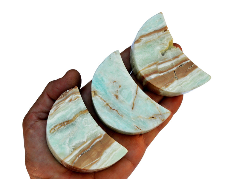 Three caribbean calcite moon crystals 65mm on hand with white background