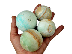 Four caribbean calcite spheres 40mm-60mm on hand with white background