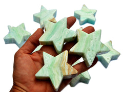 Three blue caribbean calcite star crystals 60mm on hand with background with some stars on white