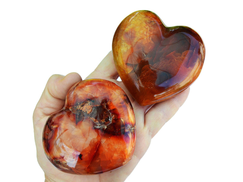 Two large carnelian heart crystals on hand with white background