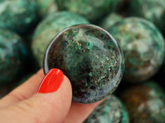 Green chrysocolla sphere crystal 35mm on hand with background with some sphere crystals