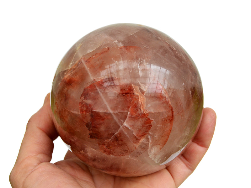 Large fire quartz sphere stone 95mm on hand with white background