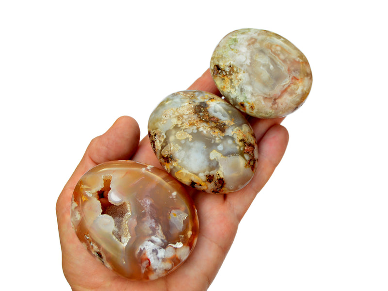 Three flower agate palm stones on hand with white background