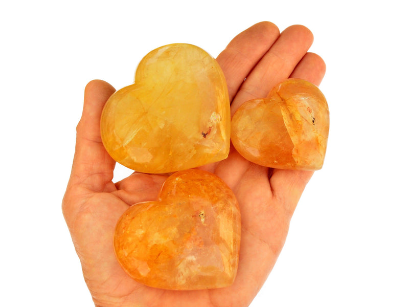 Three yellow hematoid quartz hearts 50mm-70mm on hand with white background