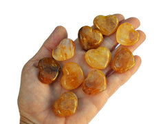 Ten golden healer quartz hearts 30mm on hand with white background