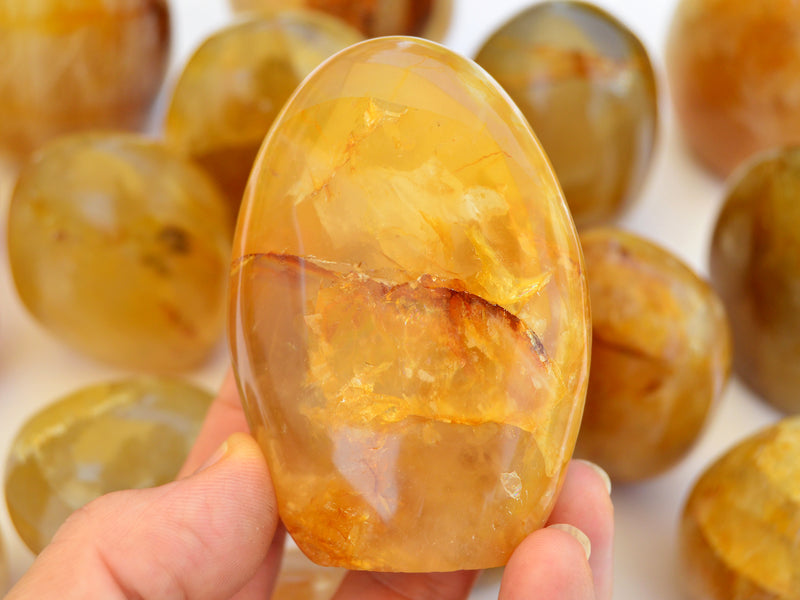 One yellow hematoid quartz on hand with background with some crystals on white