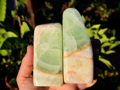 Two green caribbean calcite slabs on hand with background with green plants