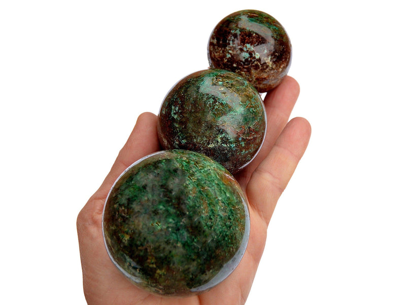 Three chrysocolla crystal spheres 40mm-65mm on hand with white background