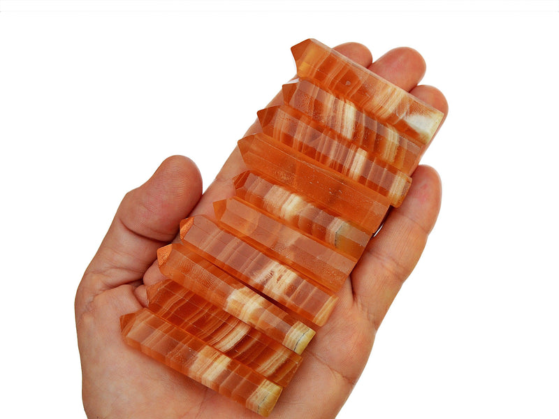 Ten banded honey calcite faceted crystal points 55mm on hand with white background