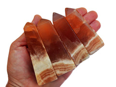 Four banded honey calcite crystal towers 60mm-90mm on hand with white background