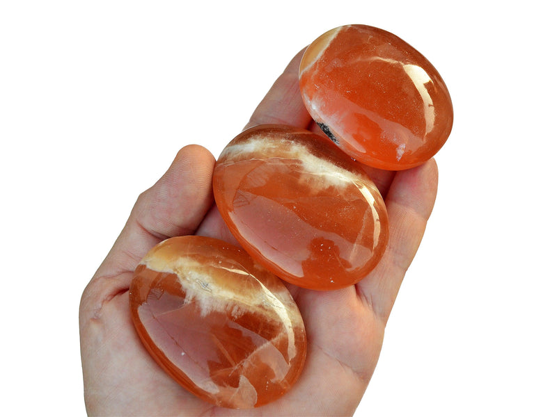 Three natural honey calcite palm stones 40mm-85mm on hand with white background