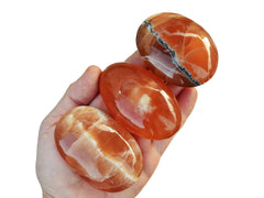 Three honey calcite palm stones 40mm-85mm on hand with white background