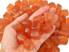 Some honey calcite mini tumbled crystals on hand with background with several stones on white