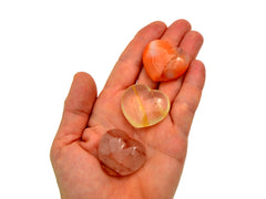 Small carnelian, fire quartz and golden healer quartz hearts 30mm on hand with white background