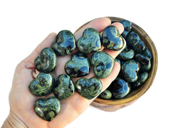 Ten kambaba jasper crystal hearts small 30mm on hand with background with some stones inside a wood bowl
