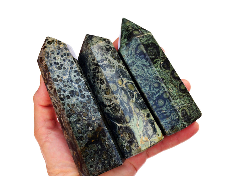 Three large crocodile jasper towers on hand with white background