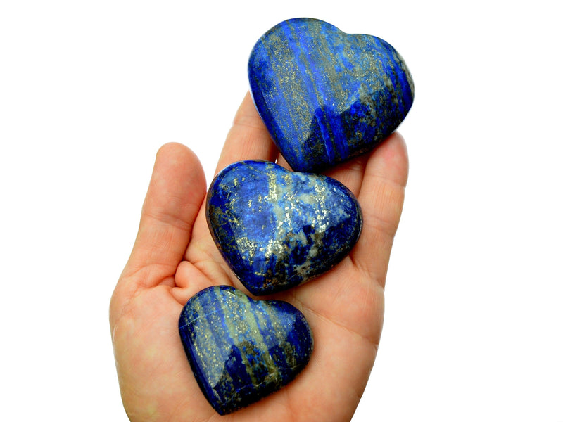 Three lapis lazuli crystals hearts 40mm-65mm on hand with white background
