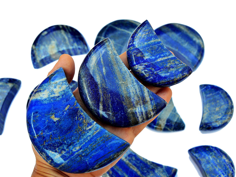 Three lapis lazuli moon carving crystals 65mm-95mm on hand with background with some moons on white
