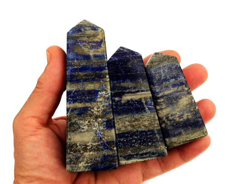 Three polished lapis lazuli crystal points 60mm-80mm held in a hand with white background